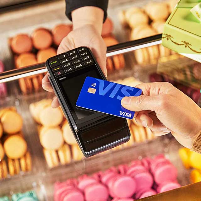 Customer using contactless payment Visa card to purchase baked goods