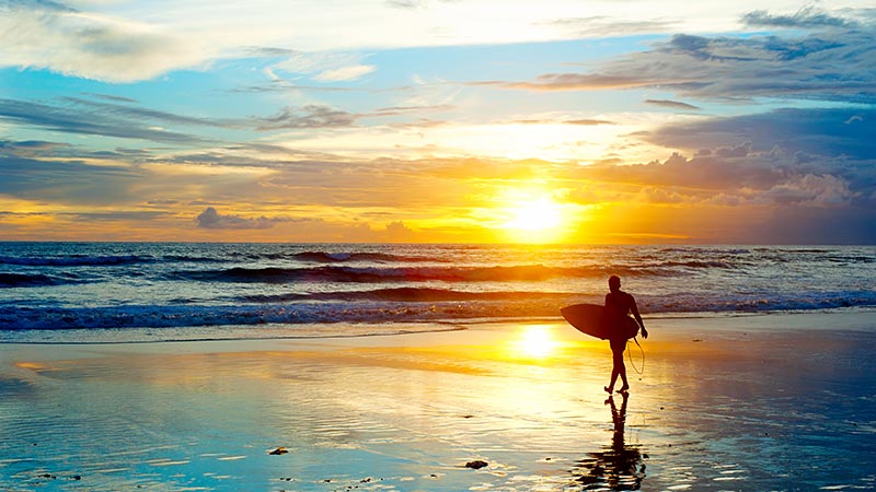 Surfer on the ocean beach at sunset on Bali island, Indonesia