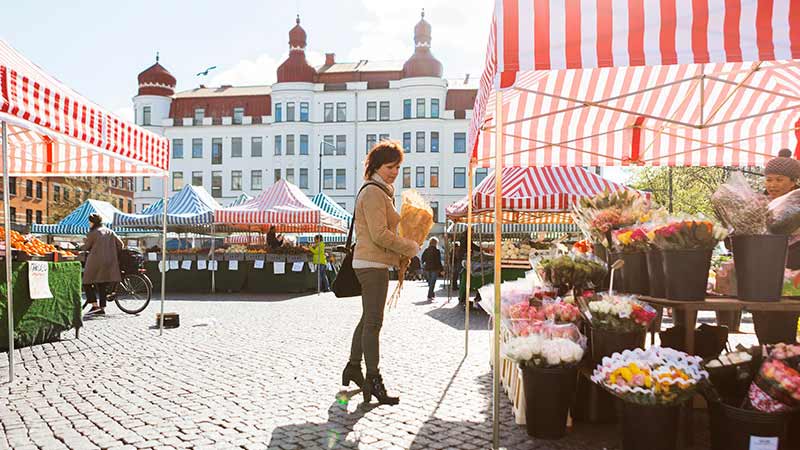 A woman at the market lookin at flowers for sale